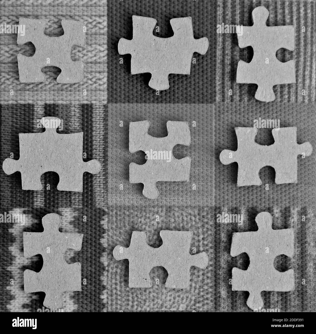 Immagine in bianco e nero di pezzi di jigsaw su un mosaico a griglia di motivi geometrici testurizzati. Foto Stock