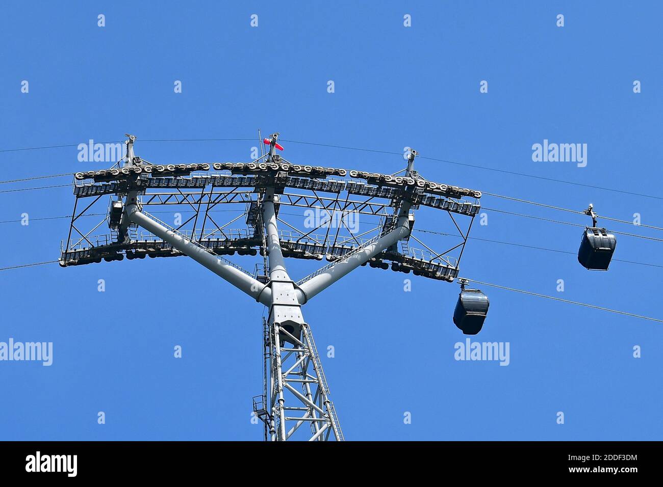 Una vista in prospettiva verso l'alto delle funivie e del pilone di supporto contro uno sfondo blu luminoso del cielo. Foto Stock