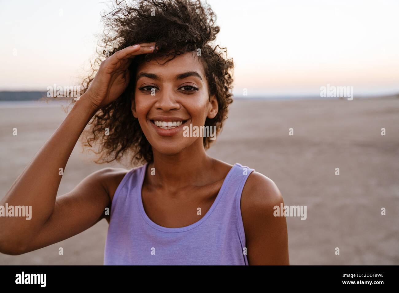 Immagine di felice donna afroamericana che posa e sorride macchina fotografica nel deserto Foto Stock