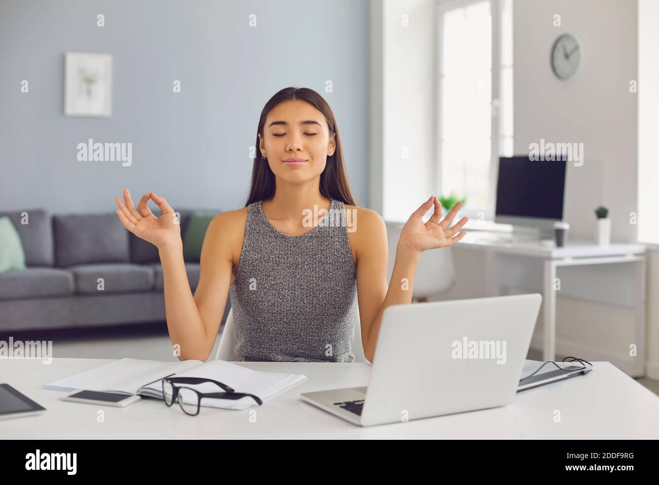 Calma donna di affari medita con i suoi occhi chiusi nel suo ufficio durante una pausa. Foto Stock