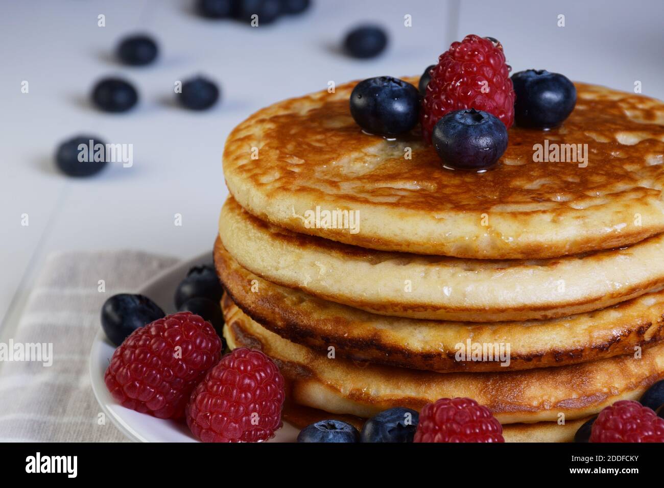 Frittelle con sciroppo d'acero, mirtilli e lamponi su tavolo di legno bianco e vista dall'alto. Foto Stock