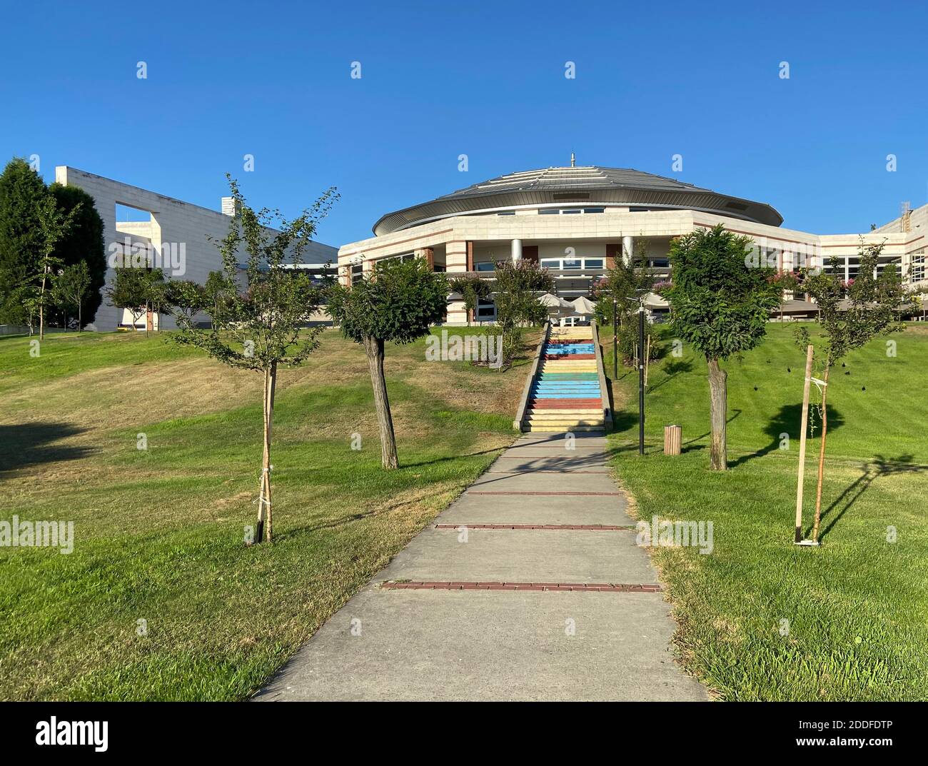 Edifici in cemento di architettura moderna. Parco naturale verde con alberi, piante e laghetto con foglie di loto. Bellissimo posto tranquillo. Foto Stock