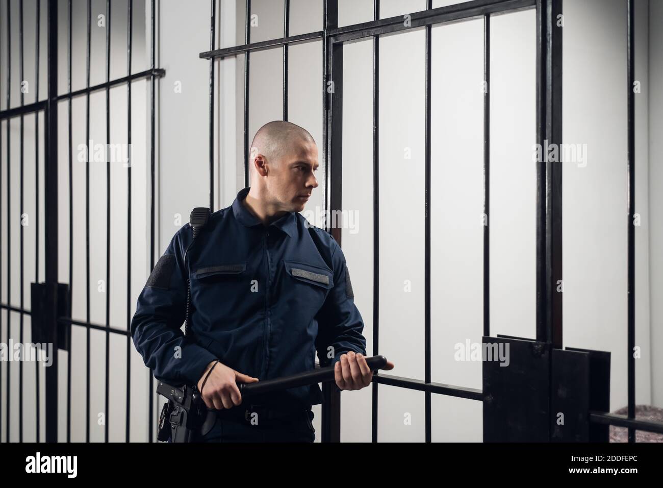 Una stretta guardia carceraria in uniforme protegge le celle con i prigionieri in una prigione di massima sicurezza Foto Stock