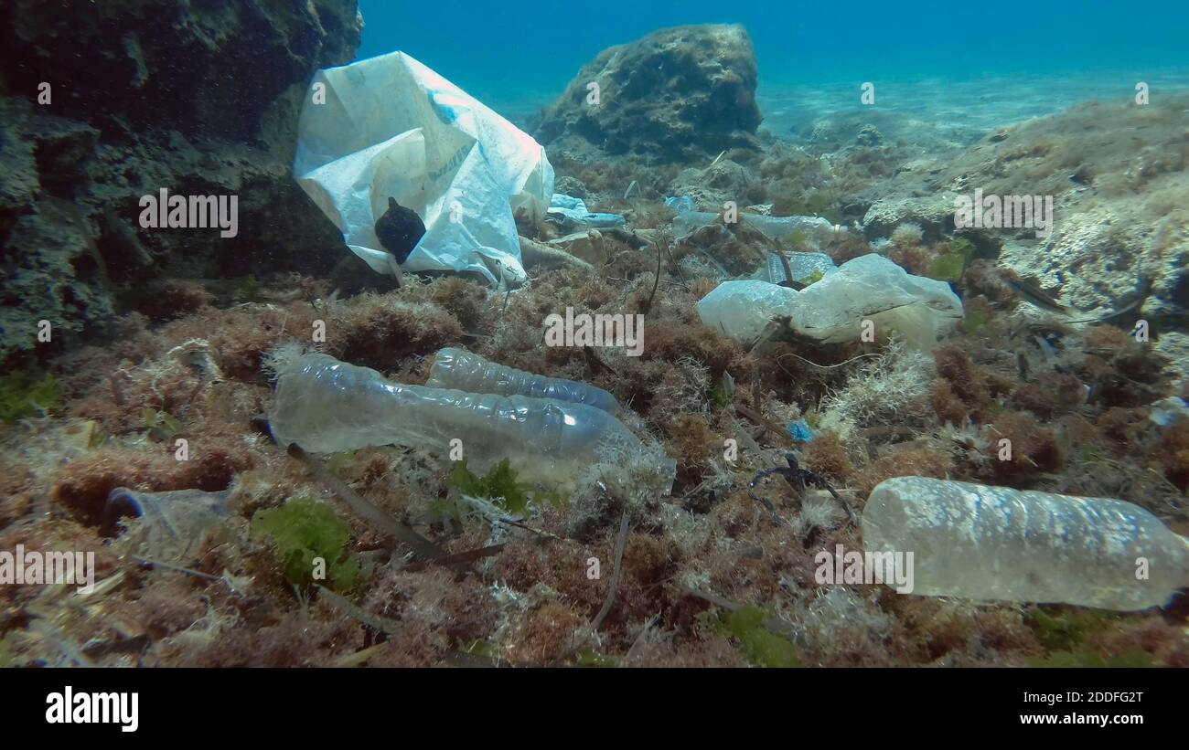 Massiccio inquinamento plastico del fondo oceanico. Fondo marino coperto con un sacco di rifiuti di plastica. Bottiglie, sacchetti e altri detriti di plastica sul fondo marino di Medit Foto Stock