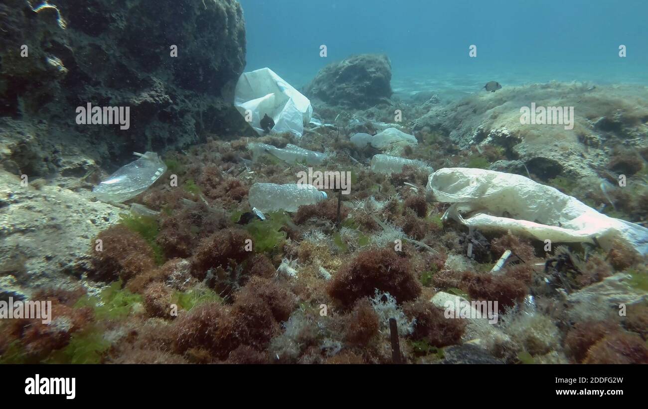 Massiccio inquinamento plastico del fondo oceanico. Fondo marino coperto con un sacco di rifiuti di plastica. Bottiglie, sacchetti e altri detriti di plastica sul fondo marino di Medit Foto Stock
