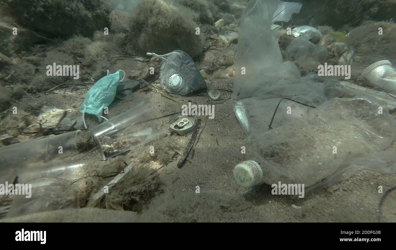 Morto più grande pesce di svezzamento (Trachinus draco) colpire intrappolato in sacchetto di plastica si trova all'interno del sacchetto di plastica sul fondo marino tra la maschera medica viso, plastica A. Foto Stock