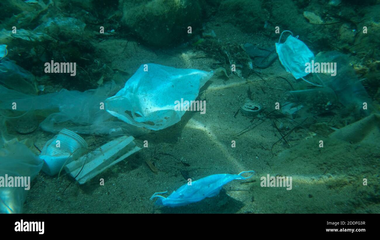 Inquinamento da plastica - bottiglie, sacchetti e altri detriti di plastica sul fondo marino. Il coronavirus COVID-19 contribuisce all'inquinamento, poiché le maschere usate scartate si ingarocchiano Foto Stock