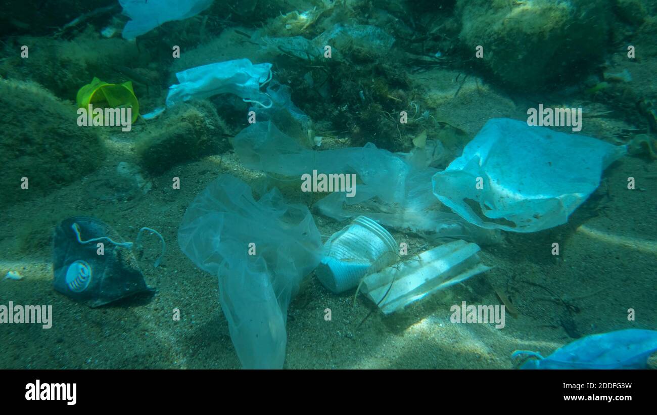 Inquinamento da plastica - bottiglie, sacchetti e altri detriti di plastica sul fondo marino. Il coronavirus COVID-19 contribuisce all'inquinamento, poiché le maschere usate scartate si ingarocchiano Foto Stock