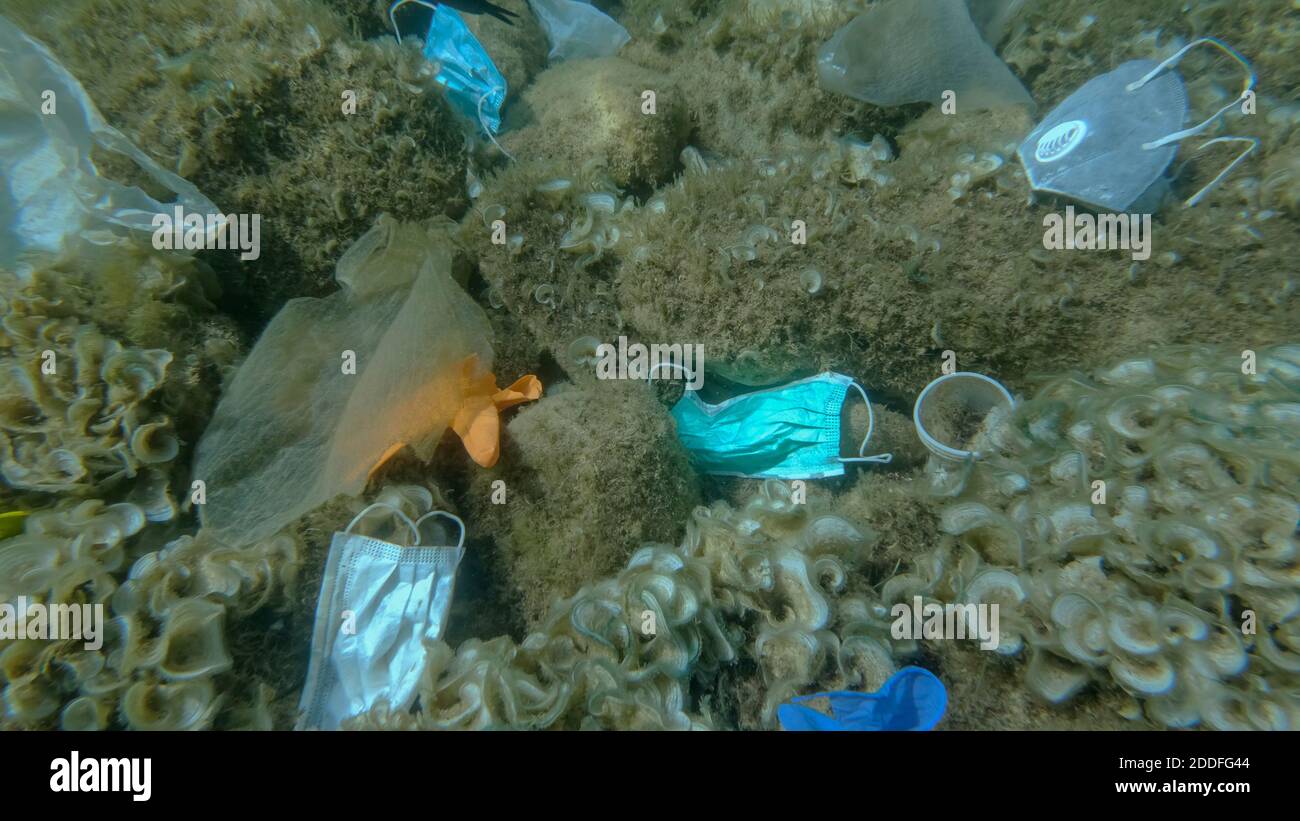 Inquinamento da plastica - bottiglie, sacchetti e altri detriti di plastica sul fondo marino. Il coronavirus COVID-19 contribuisce all'inquinamento, poiché le maschere usate scartate si ingarocchiano Foto Stock