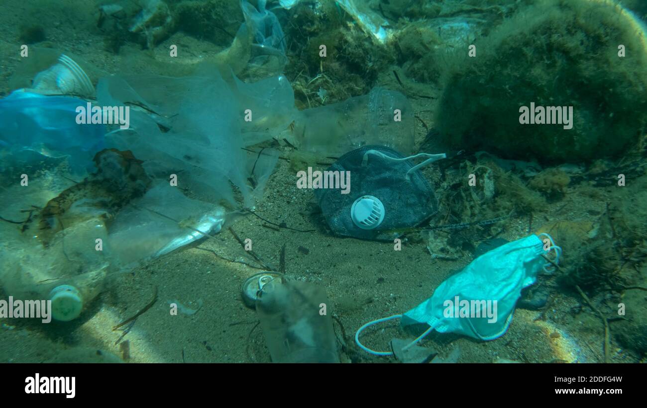 Morto più grande pesce di svezzamento (Trachinus draco) colpire intrappolato in sacchetto di plastica si trova all'interno del sacchetto di plastica sul fondo marino tra la maschera medica viso, plastica A. Foto Stock