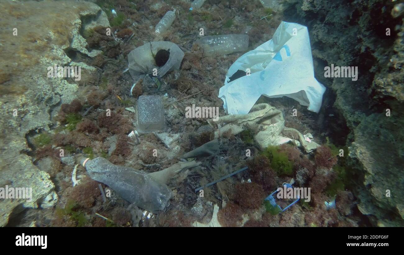 Massiccio inquinamento plastico del fondo oceanico. Fondo marino coperto con un sacco di rifiuti di plastica. Bottiglie, sacchetti e altri detriti di plastica sul fondo marino di Medit Foto Stock