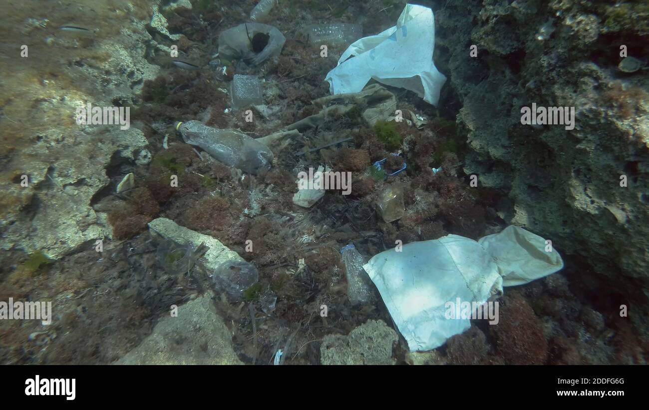 Massiccio inquinamento plastico del fondo oceanico. Fondo marino coperto con un sacco di rifiuti di plastica. Bottiglie, sacchetti e altri detriti di plastica sul fondo marino di Medit Foto Stock