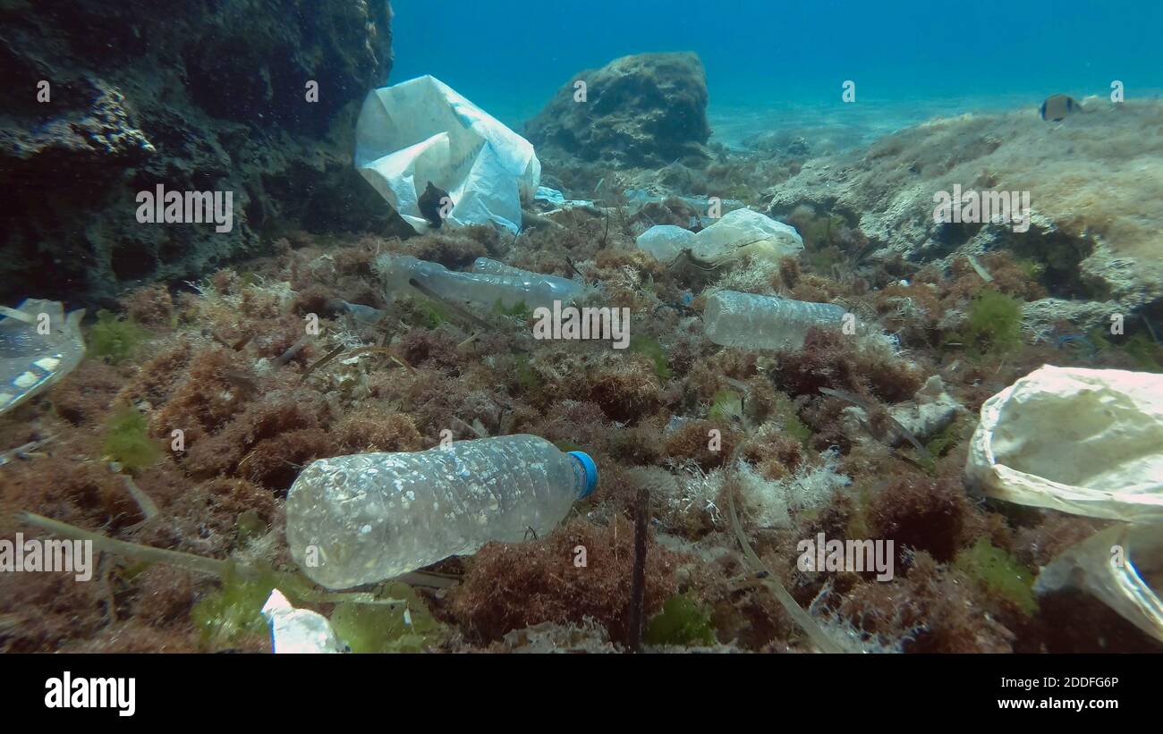 Massiccio inquinamento plastico del fondo oceanico. Fondo marino coperto con un sacco di rifiuti di plastica. Bottiglie, sacchetti e altri detriti di plastica sul fondo marino di Medit Foto Stock