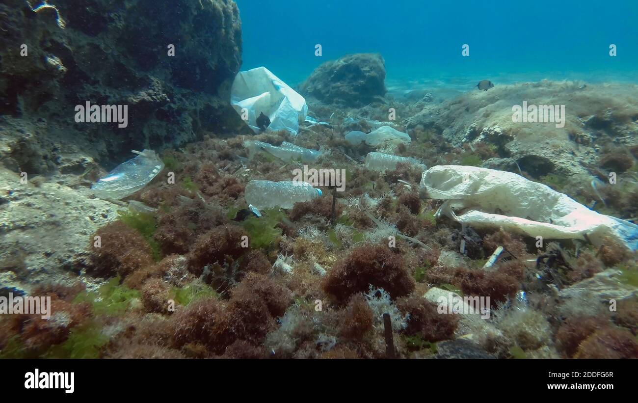 Massiccio inquinamento plastico del fondo oceanico. Fondo marino coperto con un sacco di rifiuti di plastica. Bottiglie, sacchetti e altri detriti di plastica sul fondo marino di Medit Foto Stock