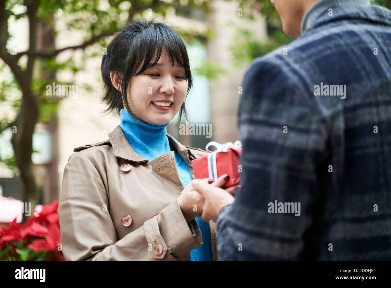 giovane uomo asiatico che dà alla fidanzata un regalo all'aperto Foto Stock