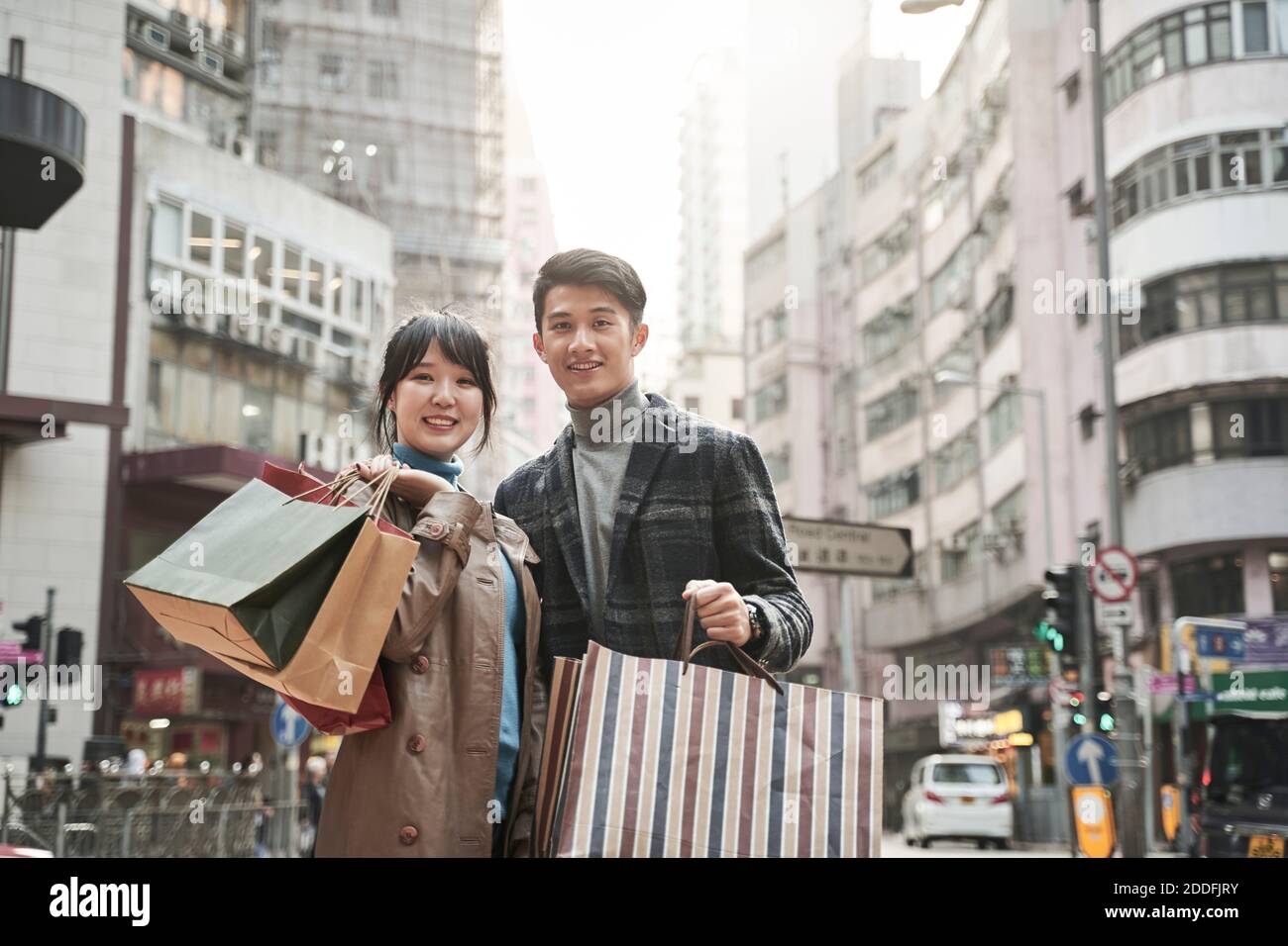 ritratto esterno di felice giovane coppia asiatica che trasporta le borse della spesa Foto Stock