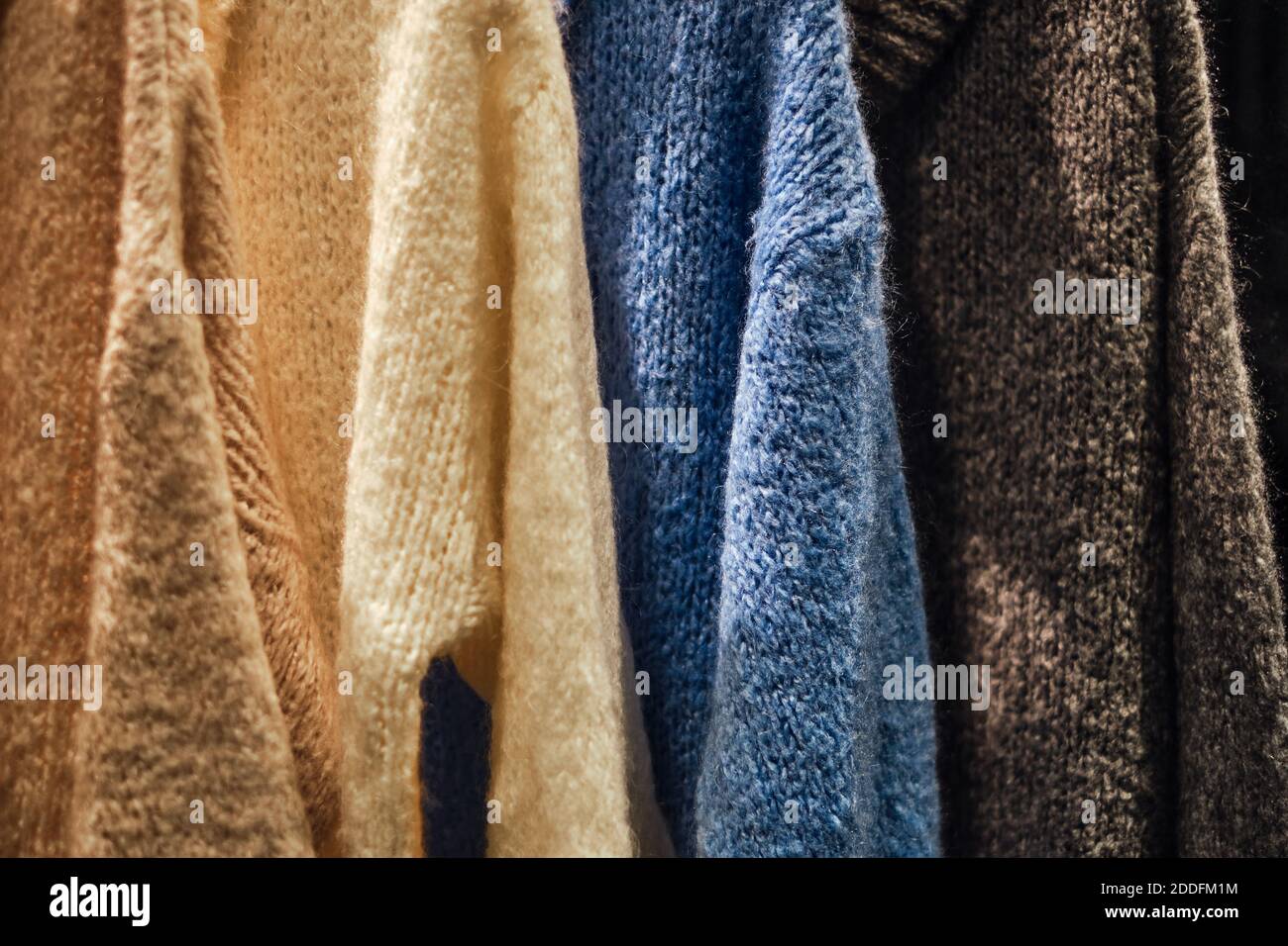 Pullover invernali lavorato a maglia su una rastrelliera in un negozio di moda. Immagine concettuale di Capsule wardrobe dei pullover nel negozio di panni. Pullover caldi fatti a mano in lana. Foto Stock