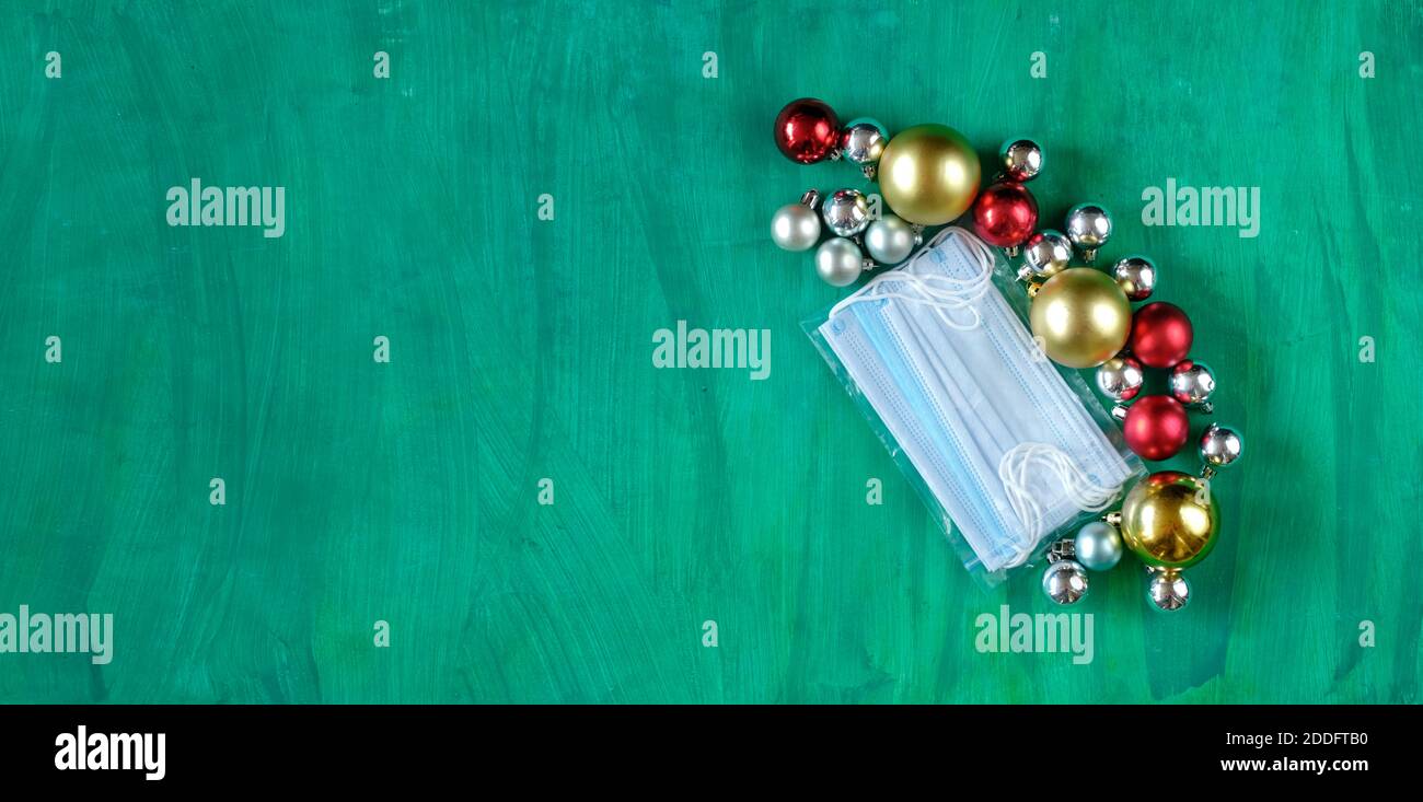 Natale in tempi di Covid-19, sola serata di natale, maschere chirurgiche viso e palle di natale, spazio libero copia, immagine simbolica Foto Stock