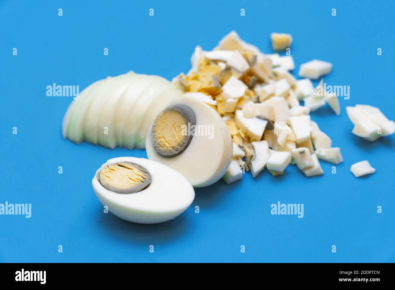 Uova bollite tagliate o tagliate a pezzi piccoli su un Tagliere Foto Stock