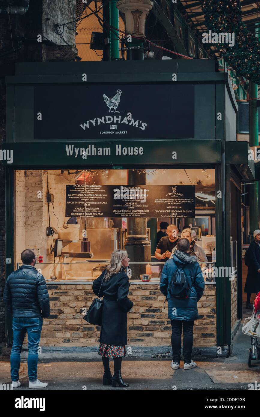 Londra, Regno Unito - 19 novembre 2020: La gente socialmente distanziata accodarsi ad un Wyndham take away food stall in Borough Market, uno dei più grandi e più antichi f Foto Stock
