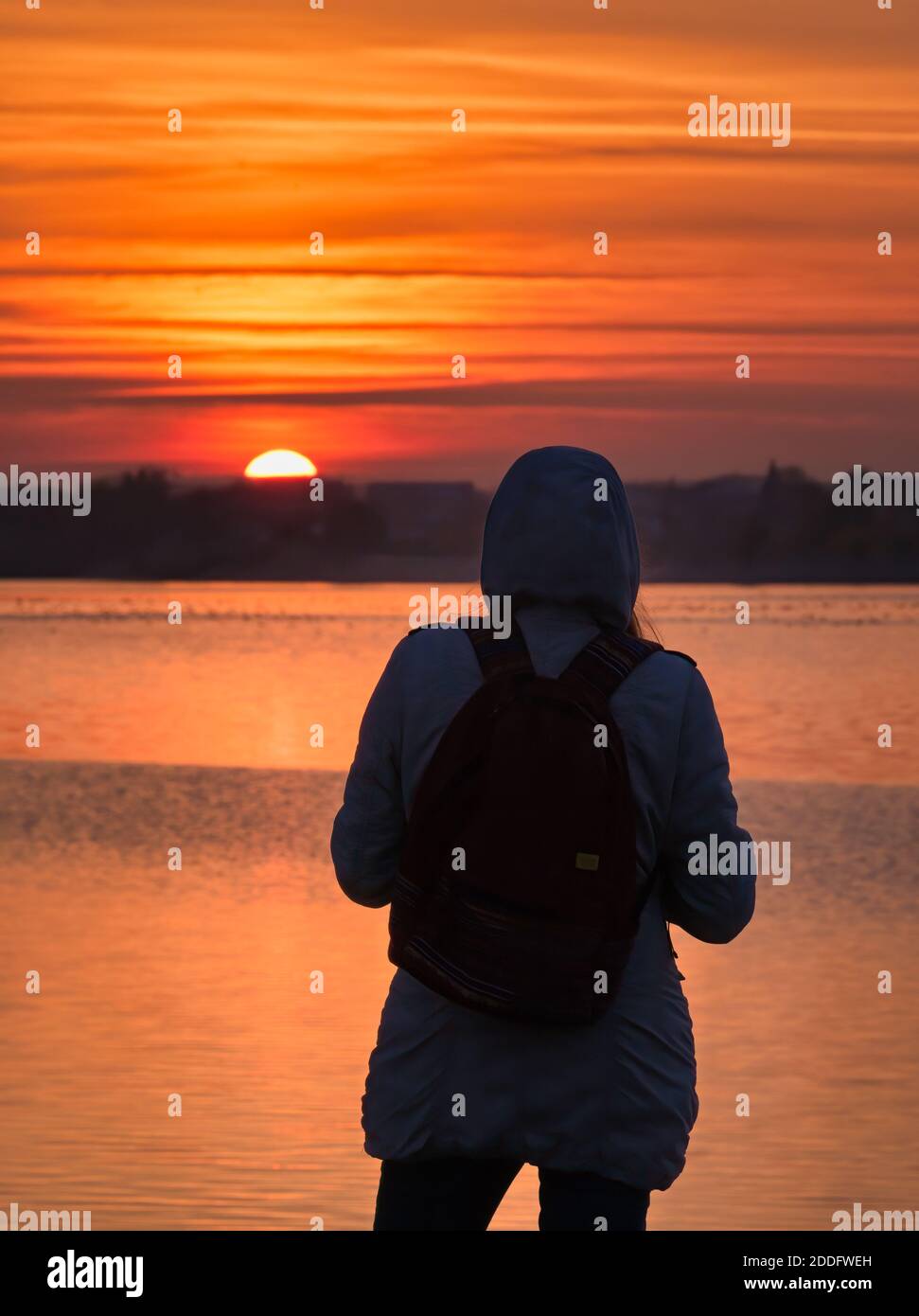 Ragazza che ammira il bellissimo tramonto ai margini di un lago. Foto Stock