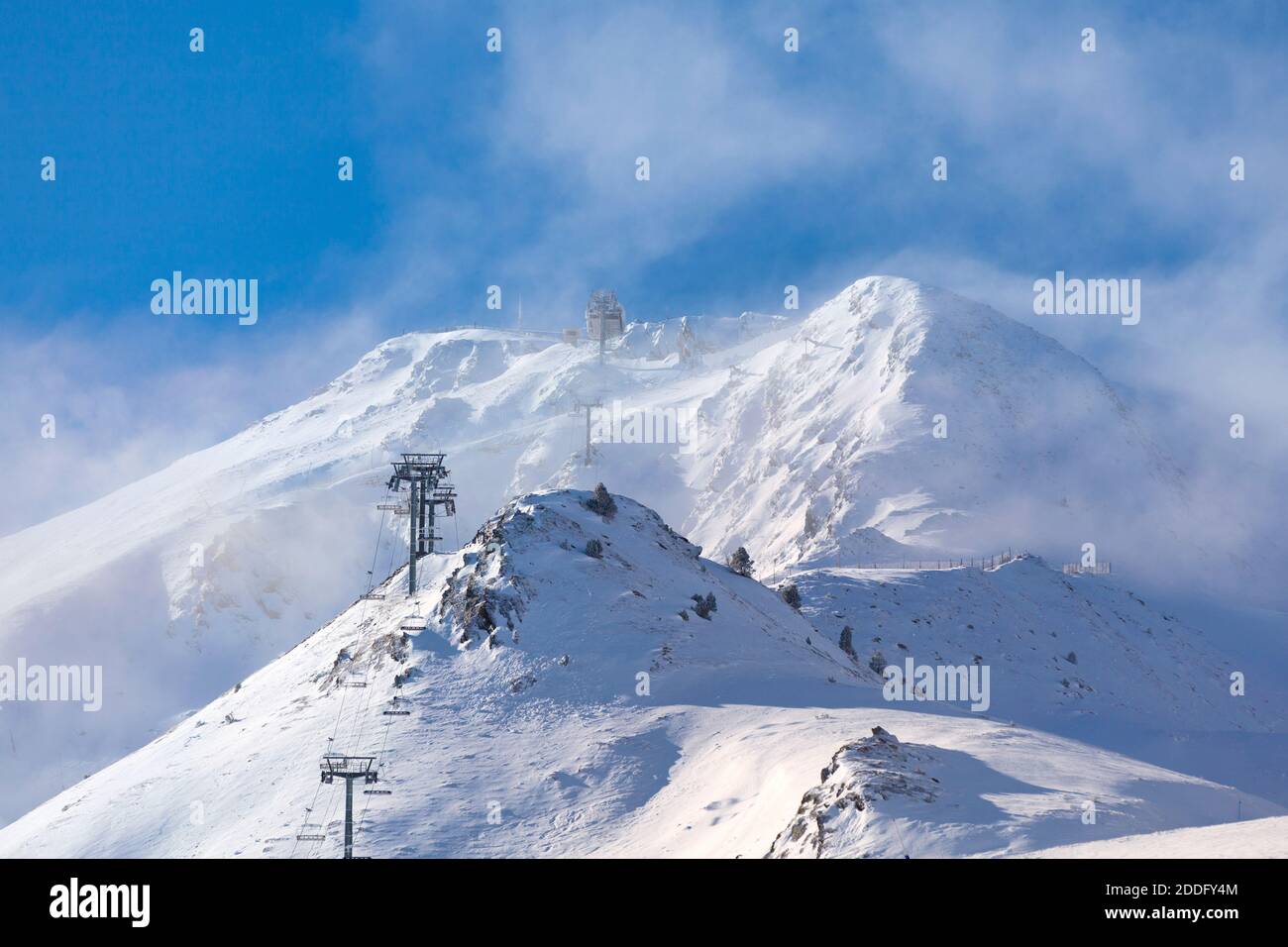 Impianti di risalita vuoti che si dirigono verso la cima della montagna innevata perduta nella nuvola. Foto Stock