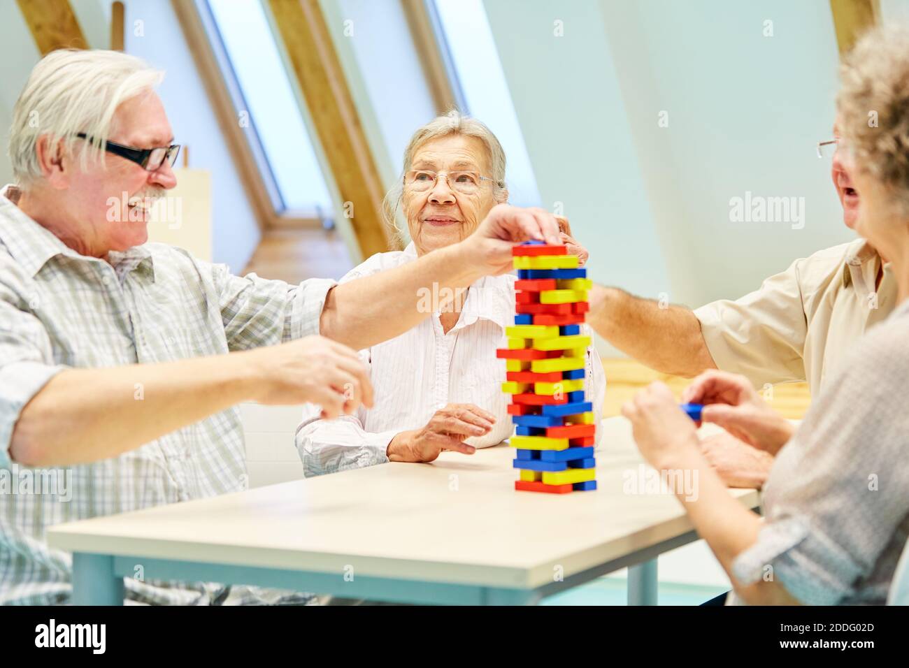 Felice gruppo di anziani in casa di riposo gioco con la costruzione blocchi come occupazione Foto Stock