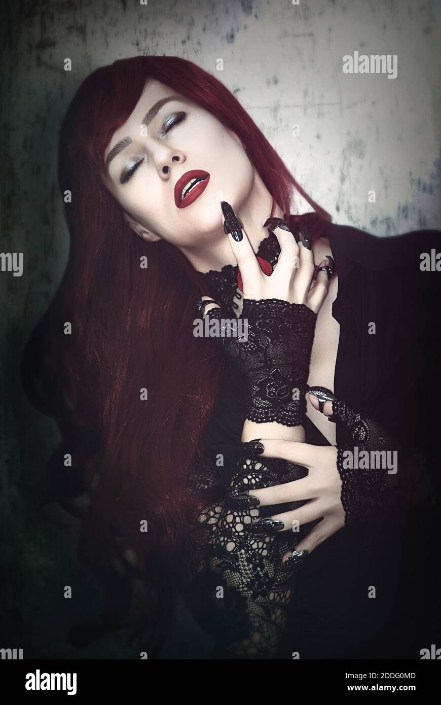 Una donna è un vampiro con capelli rossi e artigli neri. Foto Stock