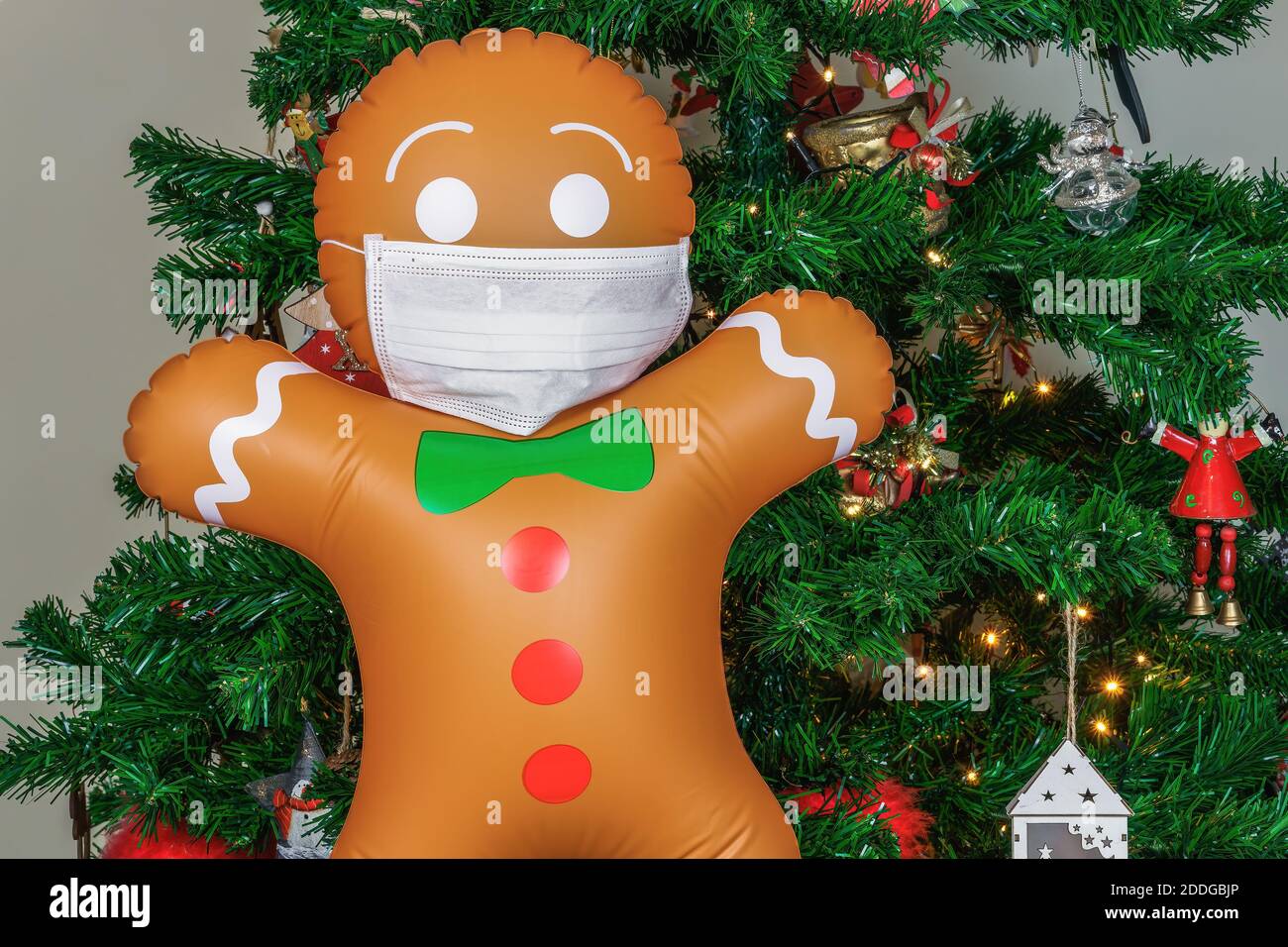 Grande biscotto gonfiabile uomo con covid-19 maschera come decorazione su albero di Natale. Soffiato aria stagionale pan di zenzero figura prima illuminato artificiale de Foto Stock