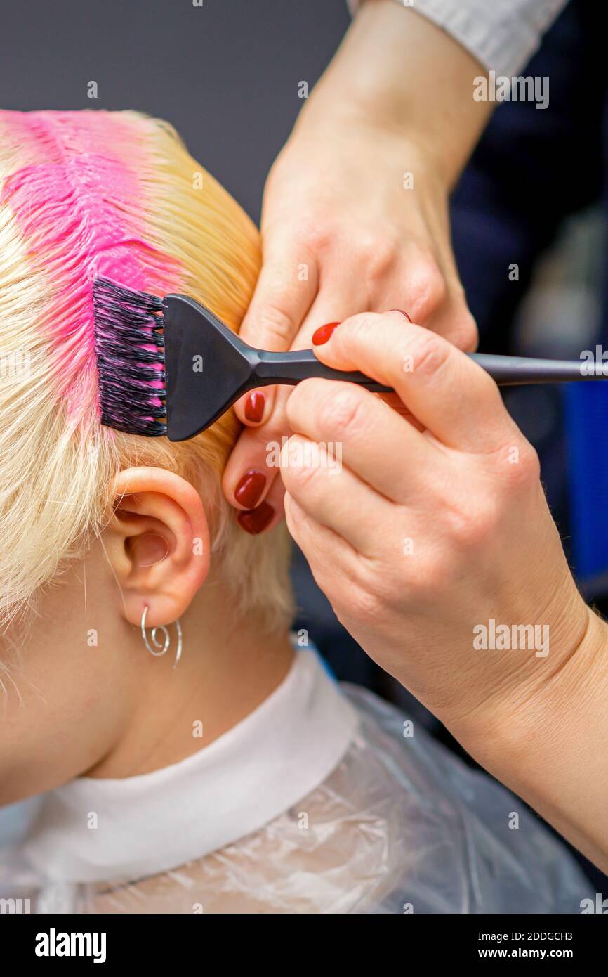 Mano con pennello tinta capelli bianchi di donna in rosa colore al  parrucchiere Foto stock - Alamy