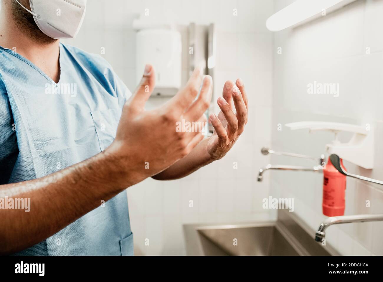 Vista laterale del raccolto irriconoscibile chirurgo che lavano le mani sopra il lavello durante la preparazione per la procedura medica in ospedale Foto Stock