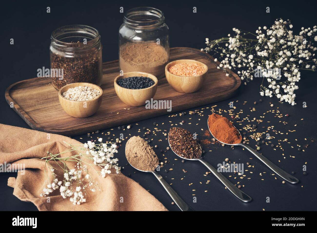 Vista dall'alto di cereali assortiti in vasi e spezie aromatiche in  cucchiai disposti su vassoio di legno su tavolo nero Foto stock - Alamy