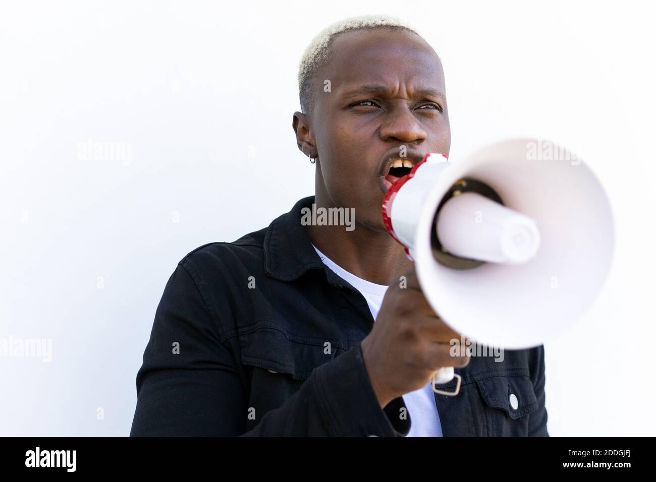Allegro maschio afroamericano gridando in altoparlante mentre si sta in piedi sfondo bianco Foto Stock