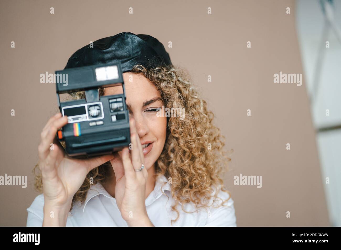 Fotografo femminile con fotocamera retrò istantanea per scattare foto sfondo marrone in studio Foto Stock