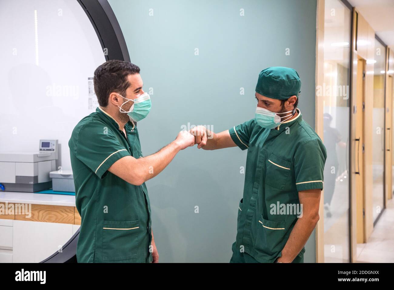 Vista laterale i medici maschi che fanno il pugno gesto mentre si è in piedi nel corridoio dell'ospedale Foto Stock