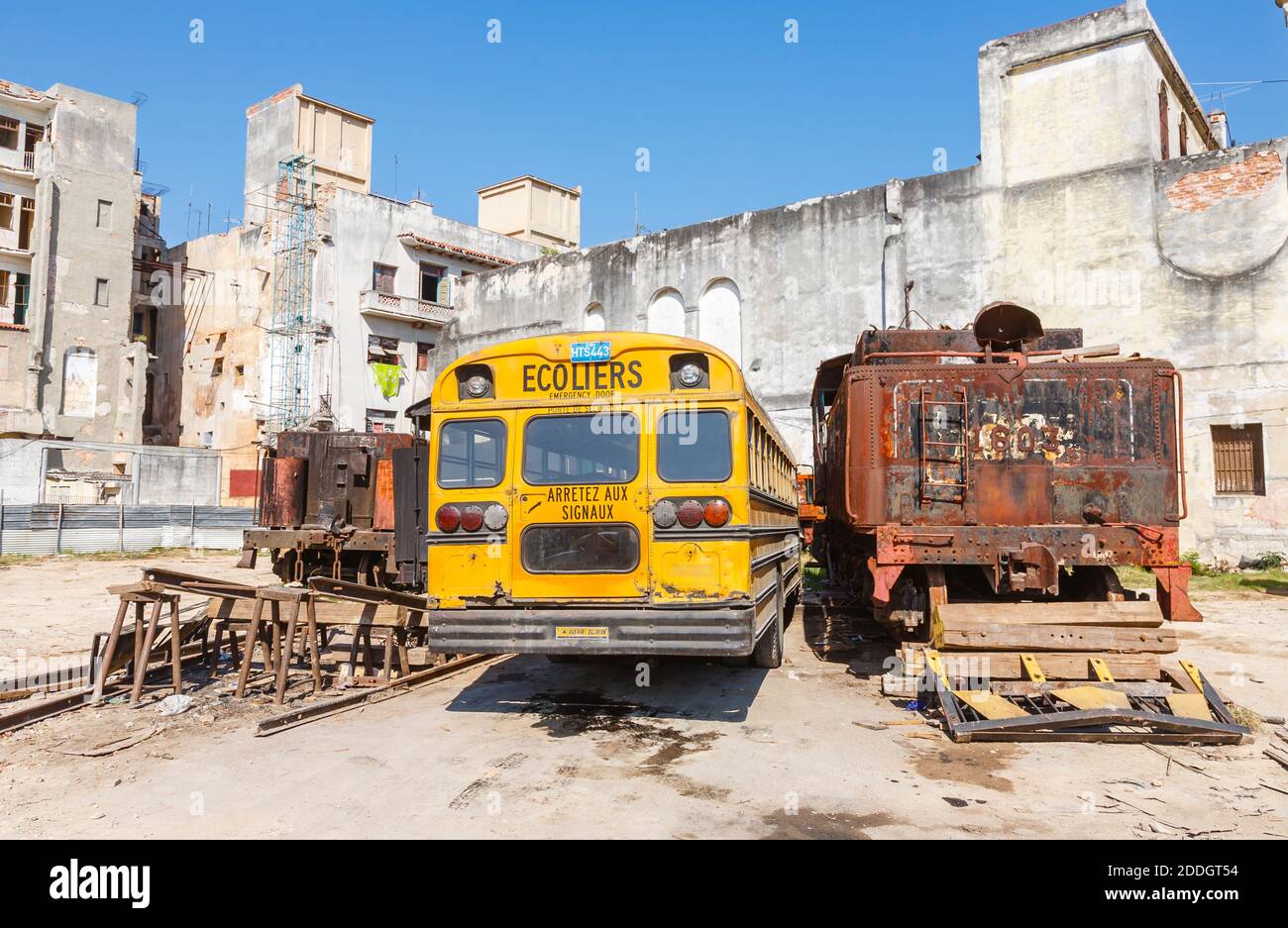 Un tipico autobus scolastico giallo vintage Blue Bird parcheggiato in un cantiere ferroviario nel centro di Old Havana, capitale di Cuba Foto Stock