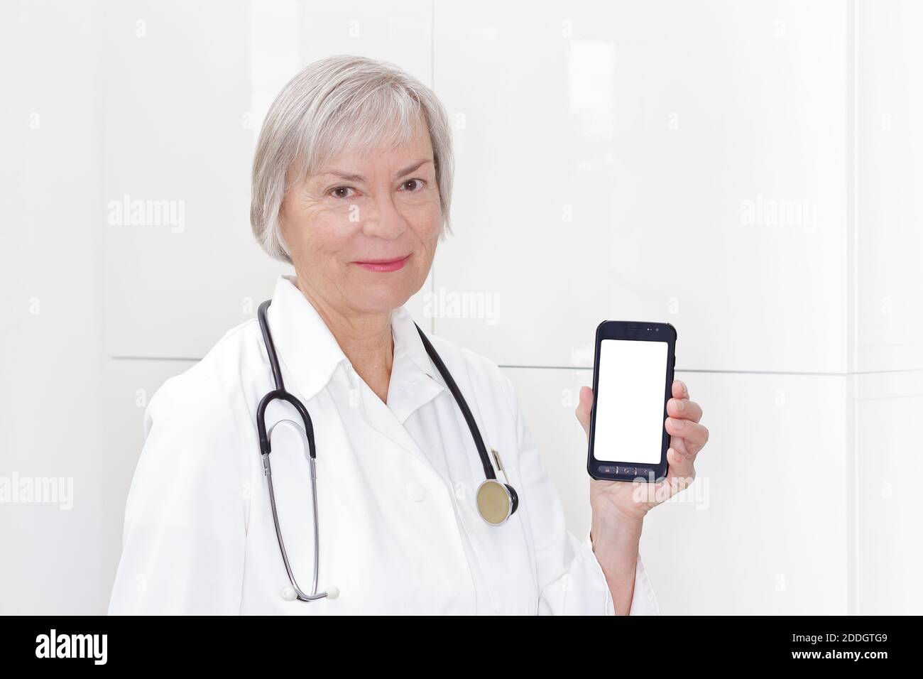 Medico senior amichevole che tiene uno smartphone, cellulare o cellulare, copyspace bianco. Modello e-Health. Foto Stock