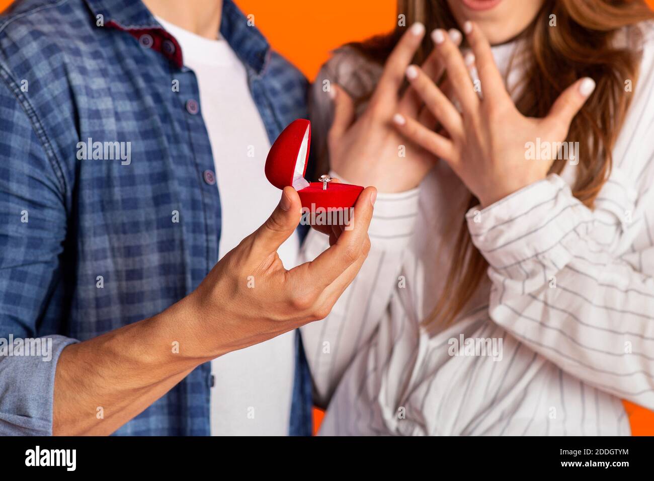 Mettere a fuoco su scatola con anello in mano maschio forte e. gesti eccitati di donna felice e sorpresa Foto Stock