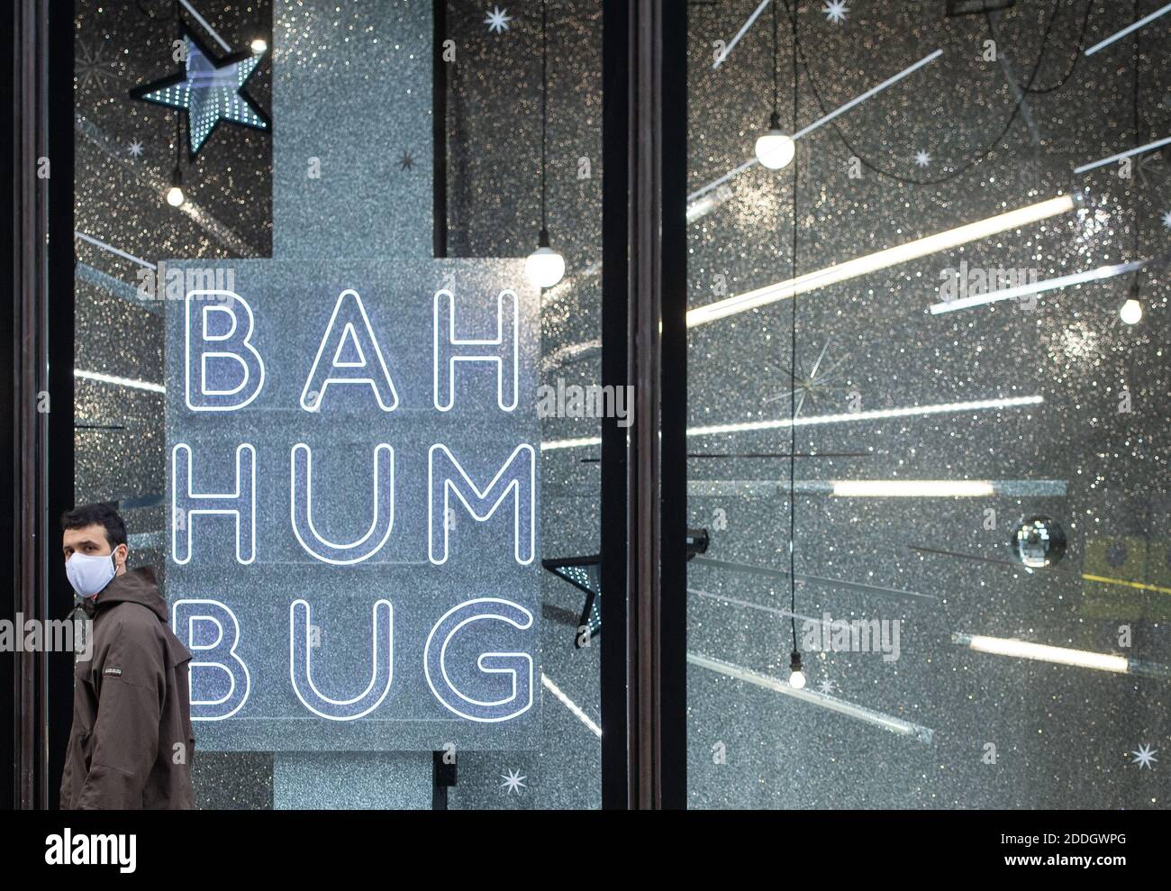 Un uomo che indossa una maschera passa una vetrina natalizia con la scritta 'Bah Humbug', nel centro di Londra, mentre l'Inghilterra si avvicina all'ultima settimana di un blocco nazionale di quattro settimane per frenare la diffusione del coronavirus. Foto Stock