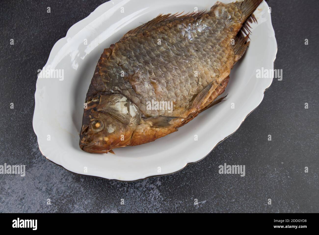 Primo piano di pesce fritto su un piatto bianco . Sfondo chiaro, Foto Stock