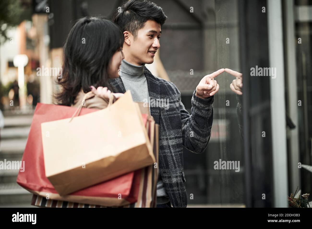 felice giovane coppia asiatica guardando in una vetrina mentre shopping nella città moderna Foto Stock felice giovane coppia asiatica guardando in una vetrina mentre shopping nella città moderna Foto Stock