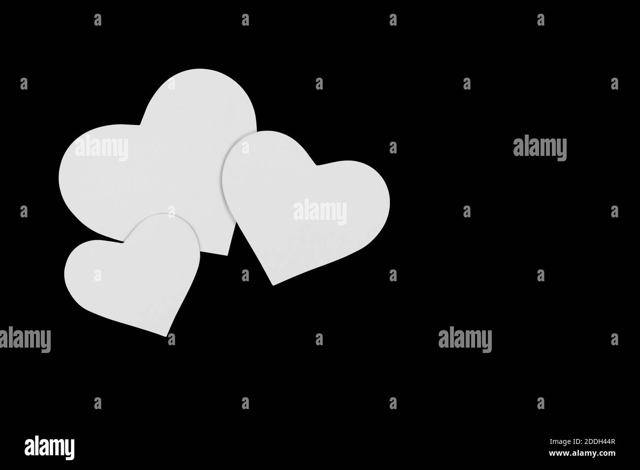 tre cuori di carta di diverse dimensioni su sfondo nero Foto Stock
