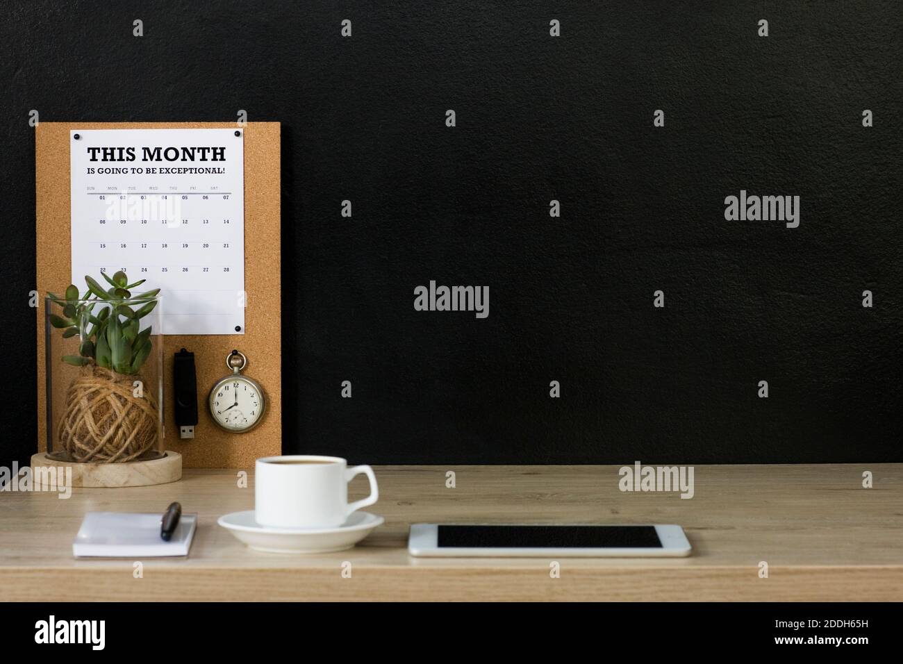 Questo ufficio domestico ha una bacheca di avviso di sughero con un calendario, un orologio da tasca vintage e un'unità flash USB fissata ad esso. La scrivania è organizzata e ordinata. Foto Stock