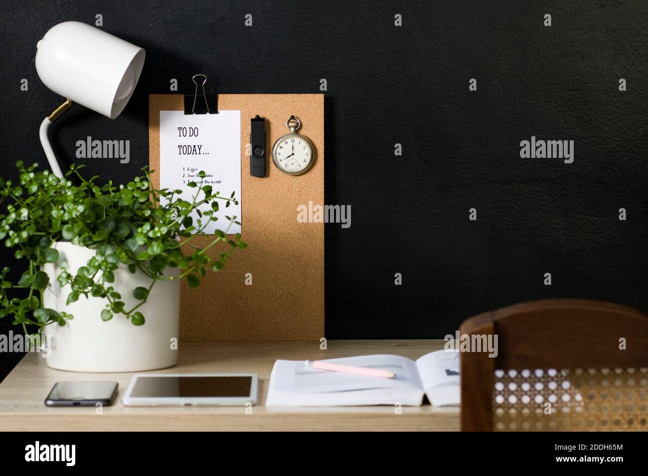 Questo ufficio domestico ha una bacheca di avviso di sughero con un calendario, un orologio da tasca vintage e un'unità flash USB fissata ad esso. La scrivania è organizzata e ordinata. Foto Stock