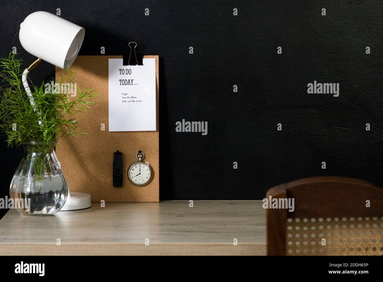 Questo ufficio domestico ha una bacheca di avviso di sughero con un calendario, un orologio da tasca vintage e un'unità flash USB fissata ad esso. La scrivania è organizzata e ordinata. Foto Stock