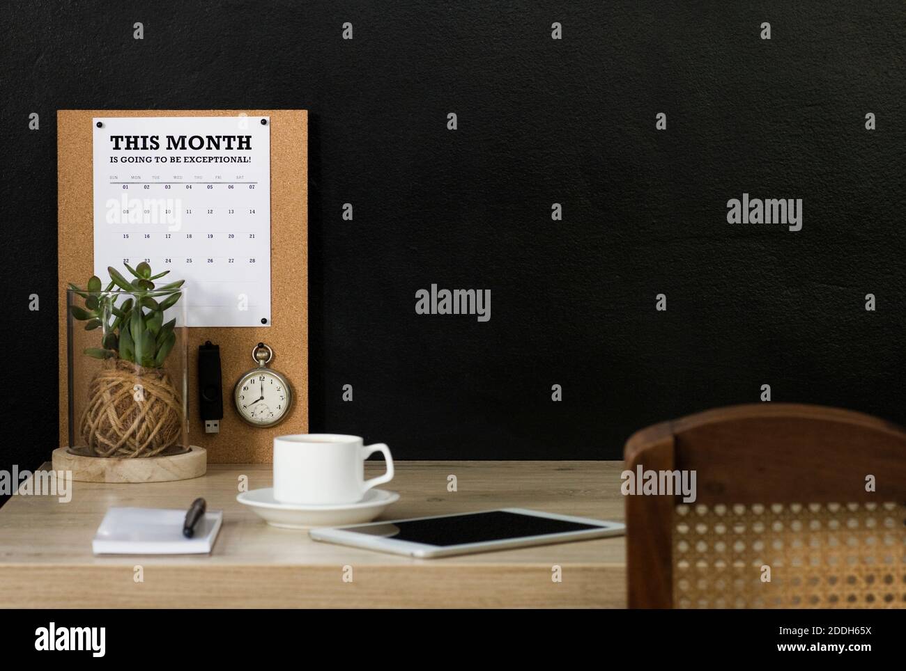 Questo ufficio domestico ha una bacheca di avviso di sughero con un calendario, un orologio da tasca vintage e un'unità flash USB fissata ad esso. La scrivania è organizzata e ordinata. Foto Stock
