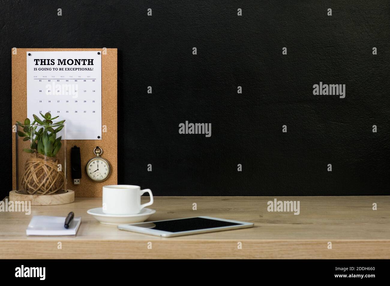 Questo ufficio domestico ha una bacheca di avviso di sughero con un calendario, un orologio da tasca vintage e un'unità flash USB fissata ad esso. La scrivania è organizzata e ordinata. Foto Stock