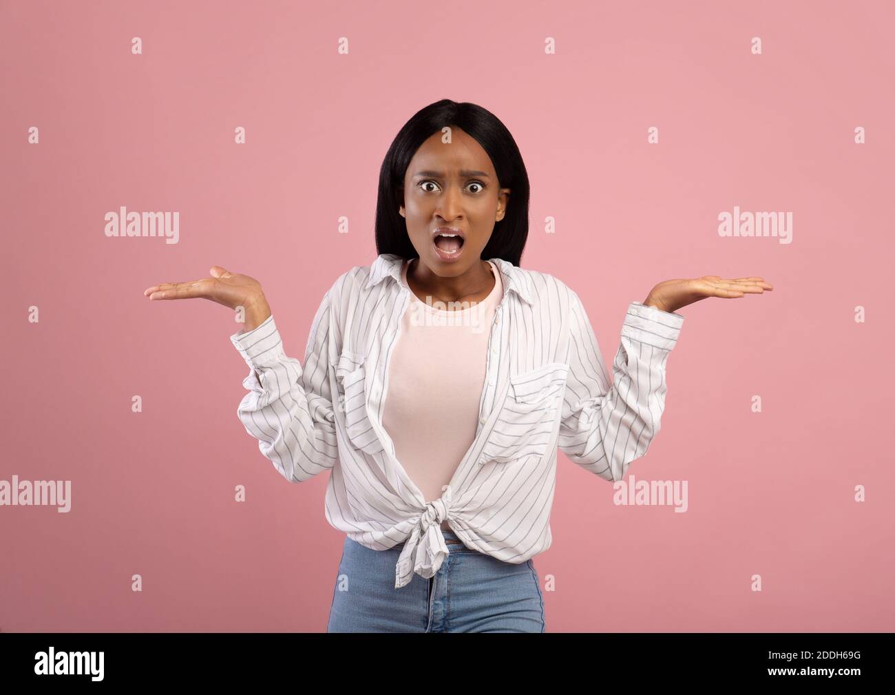 Infastidita donna afroamericana gesturing non SO, shrugging le spalle su sfondo rosa studio Foto Stock