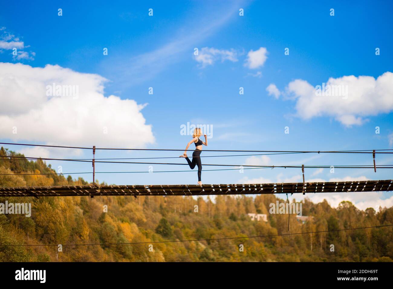 Donna atleta in forma che corre sul ponte di legno sopra le montagne del fiume. Fitness femminile jogging allenamento benessere concetto. Foto Stock