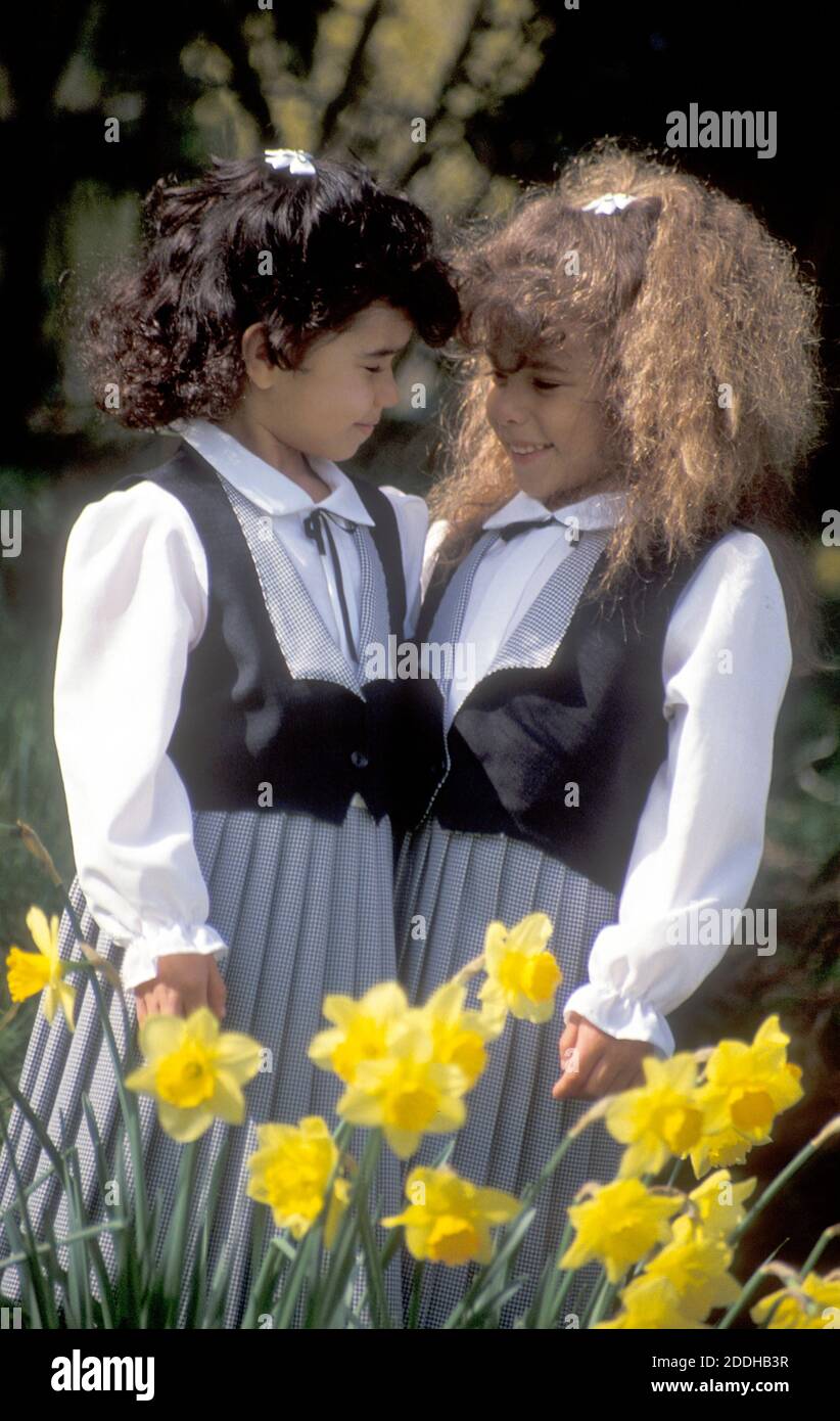due piccole sorelle in piedi in narcisi che tengono una conversazione Foto Stock